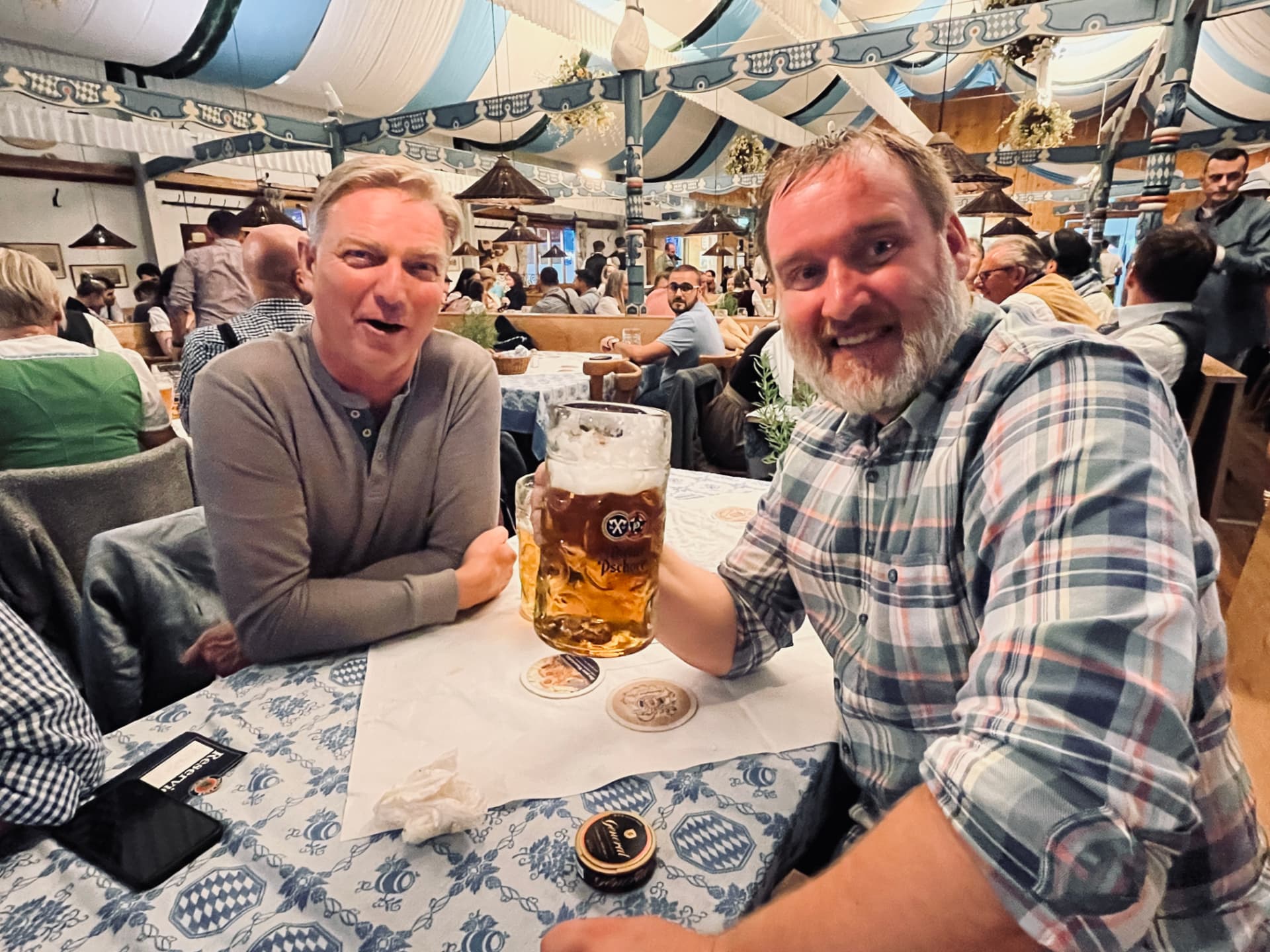Två klubbmedlemmar i lederhosen med en öl vid bordet