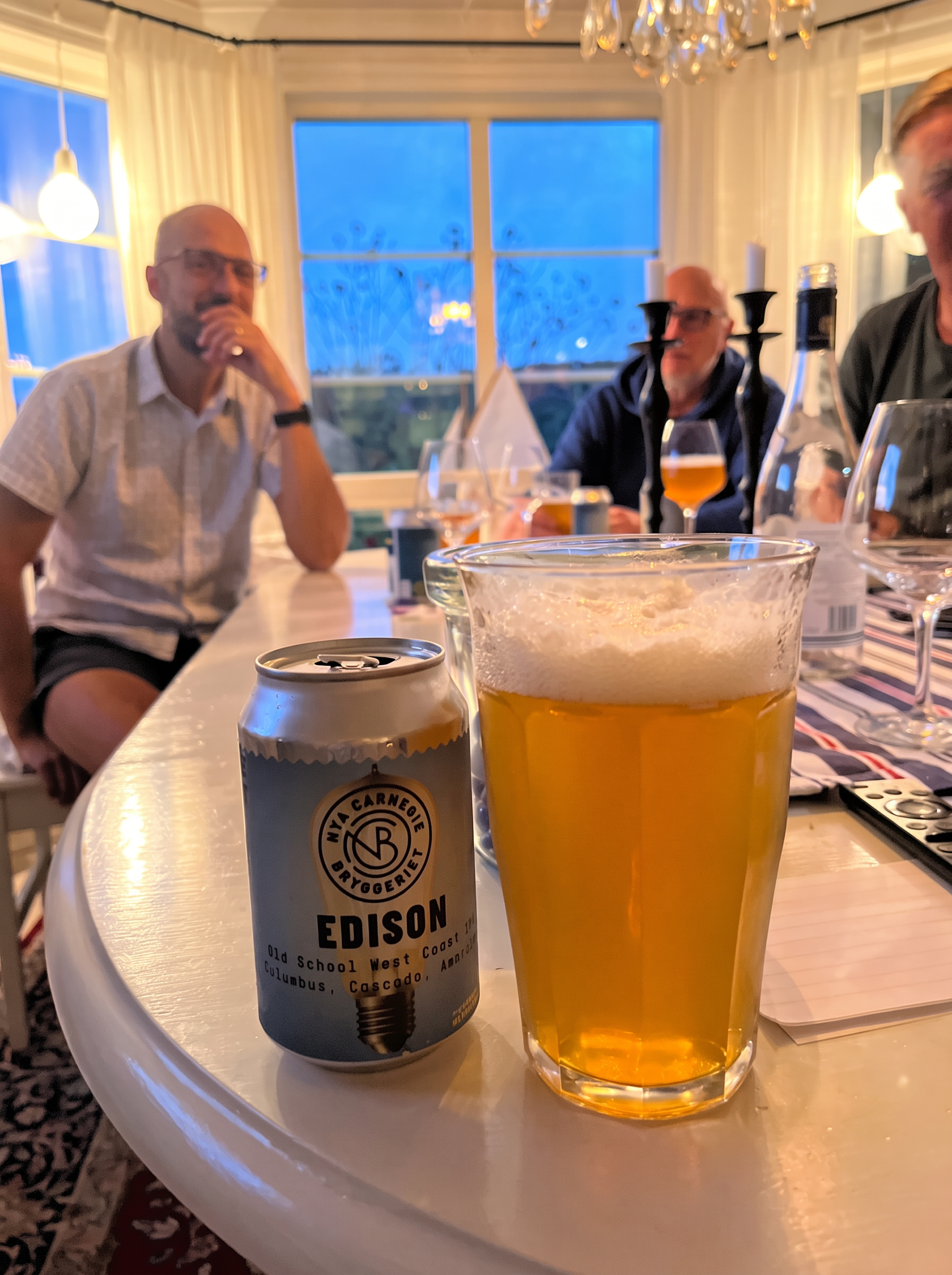Ett glas öl och en Edison-burk framför samlade klubbmedlemmar