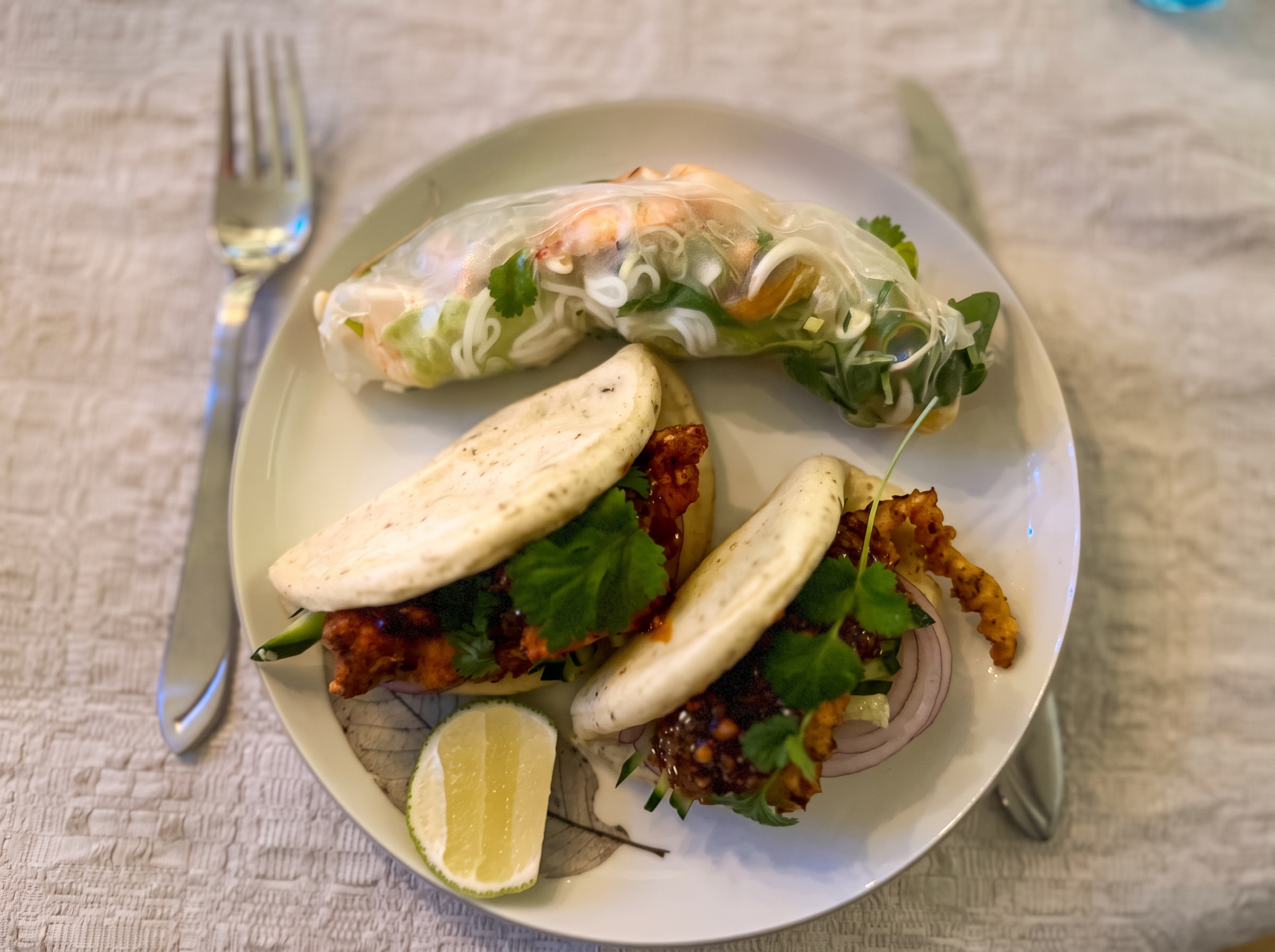 En tallrik med bao, vårrulle och lime