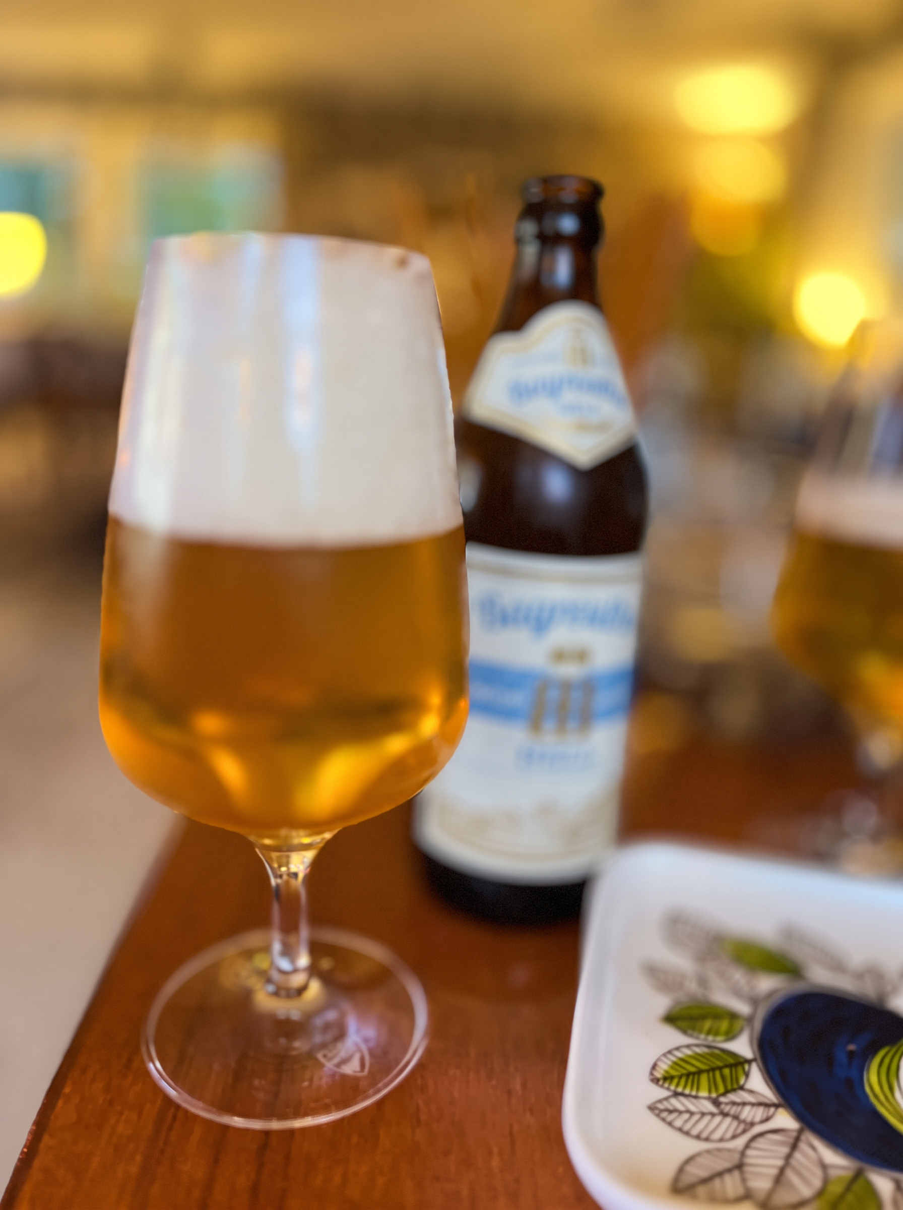 Ett glas ljust öl framför en ölflaska